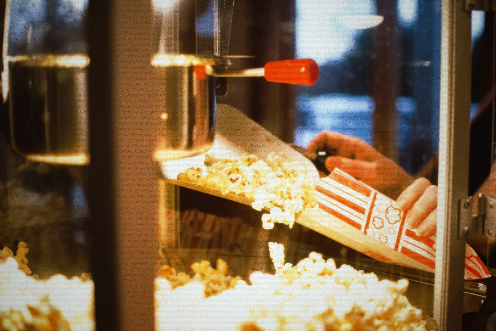 ASCII-style image of popcorn being scooped from a commercial popcorn machine into a striped bag